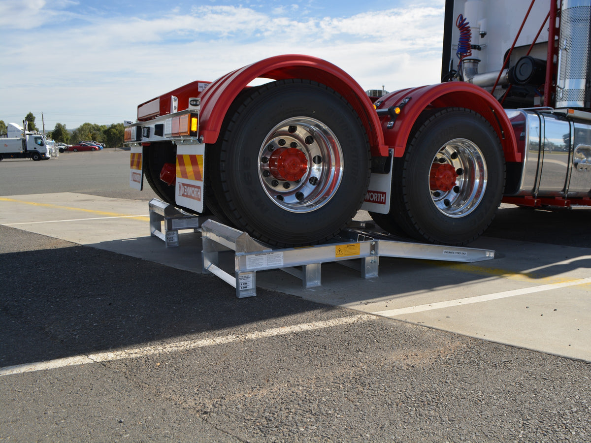 Kenworth prime mover with its rear axle dual wheels raised on a Sureweld single-axle wheel riser ramp