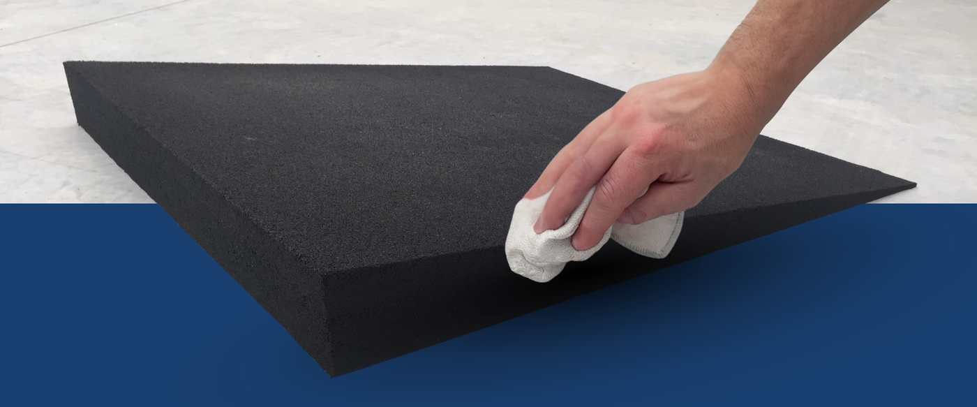 Person cleaning a rubber ramp with a white cloth on a blue and grey background