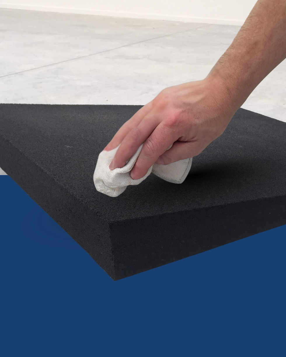 Person cleaning a rubber ramp with a white cloth on a blue and grey background