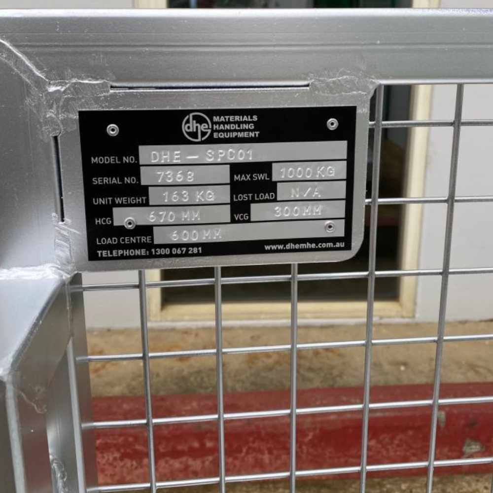 Close-up of the DHE Forklift Stock Picking Cage nameplate, displaying model number, weight capacity, and safety information. Heavy-duty steel construction for durability