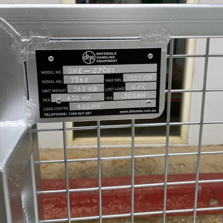 Close-up of the DHE Forklift Stock Picking Cage nameplate, displaying model number, weight capacity, and safety information. Heavy-duty steel construction for durability
