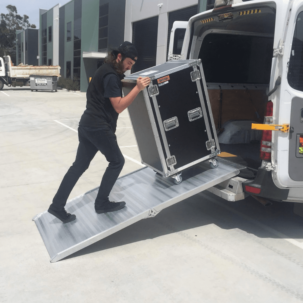 Person loading equipment into van using a folding aluminium ramp.