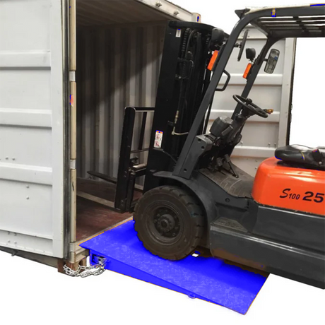 Forklift driving up blue container ramp into a shipping container