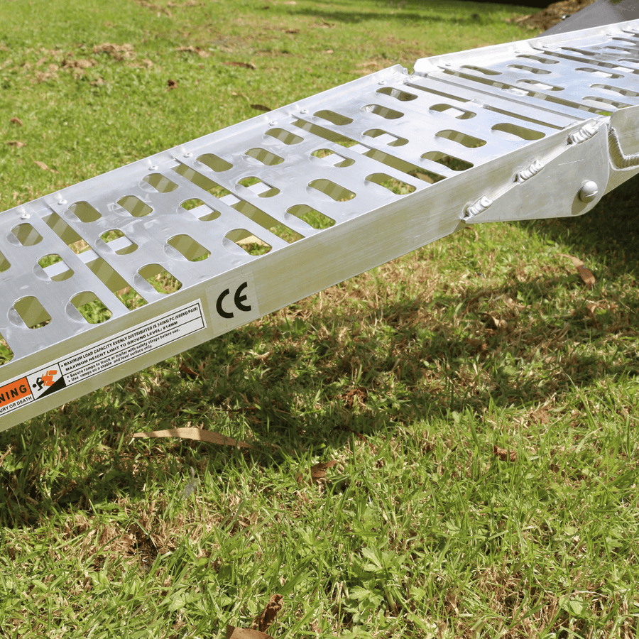 The ramp in use on grass, illustrating the anti-slip perforations and curved design for safe loading.