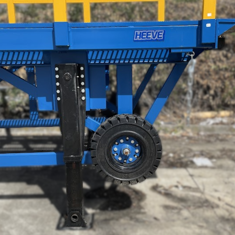 Adjustable leg and locking wheel mechanism beneath a blue loading ramp.
