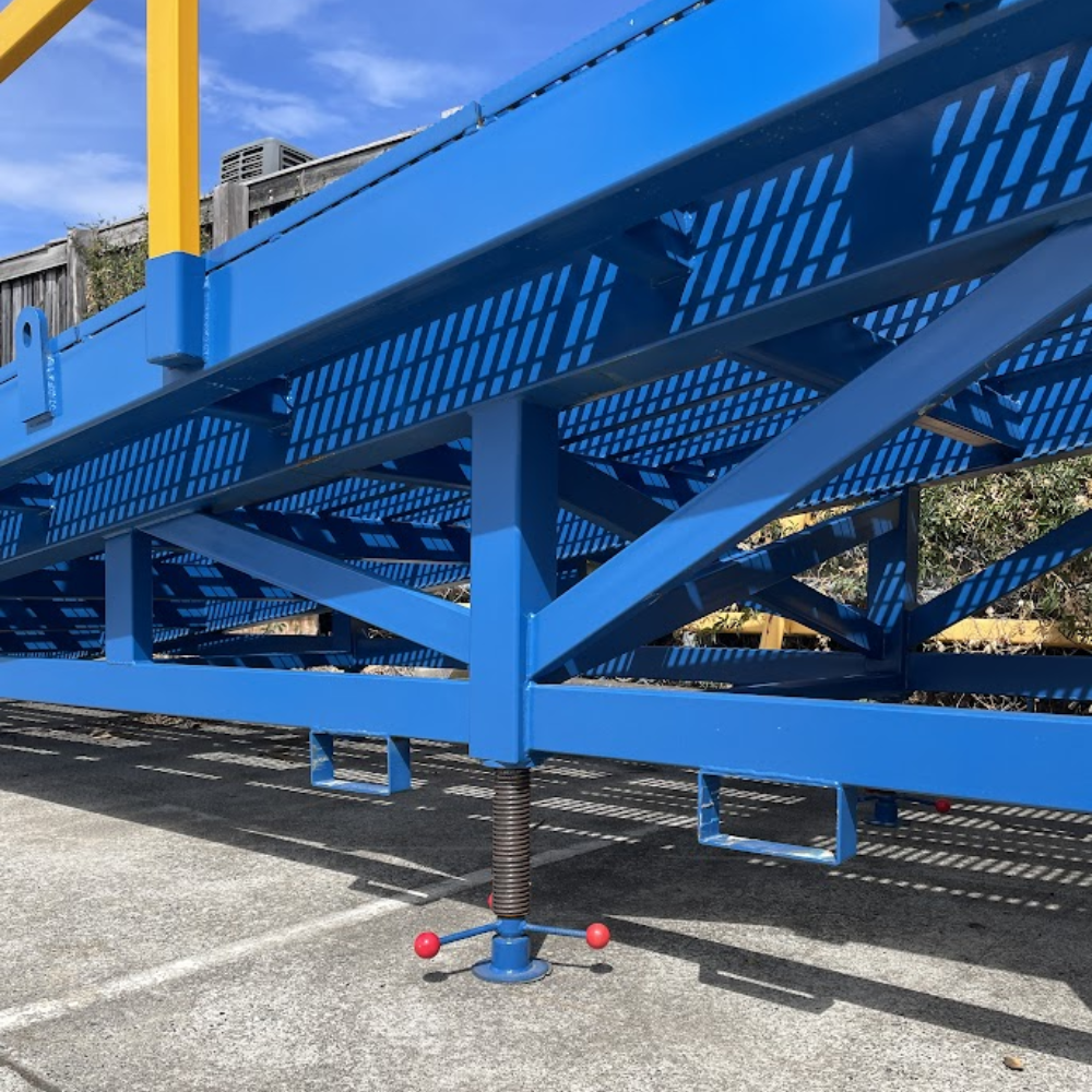 Side angle of blue mobile ramp frame showing support structure and wheels.