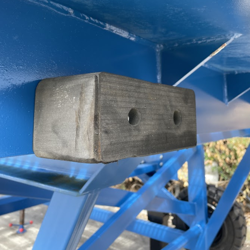 Rectangular rubber buffer mounted on side of ramp for impact protection.