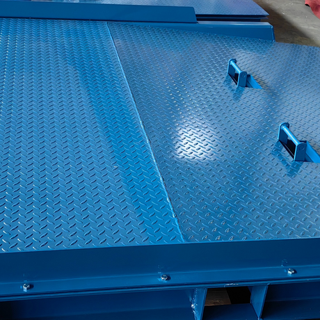 Top-down close-up of the blue dock plate showing welded lifting lugs and anti-slip surface.