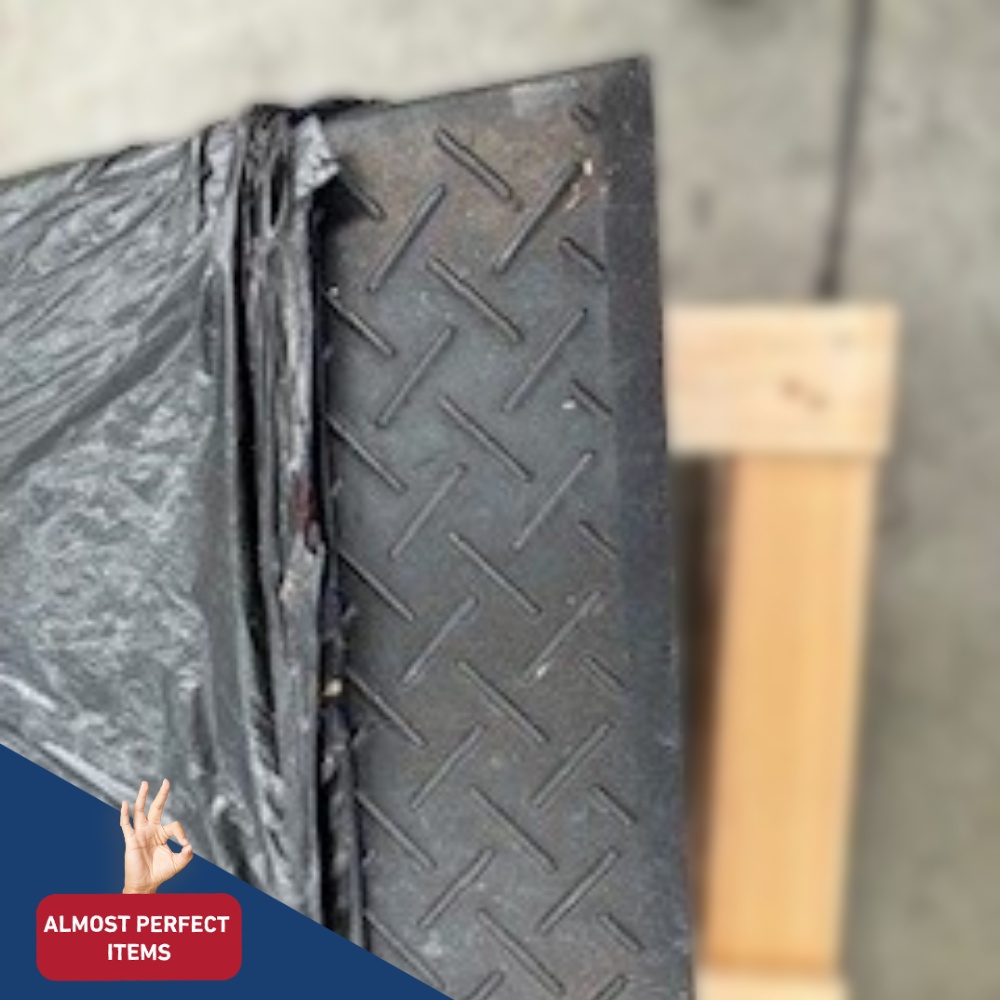 Close-up of a black, diamond-plate rubber kerb ramp, partially wrapped in plastic, labeled as an "Almost Perfect" item.