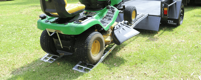John Deere lawn mower on aluminium ramps travelling up on to a grey trailer