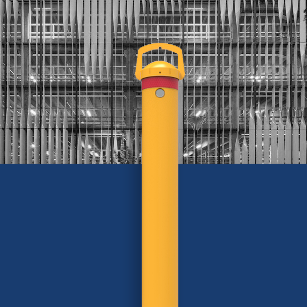 Yellow removable surface mount bollard on a blue and building background, handle and base clearly visible