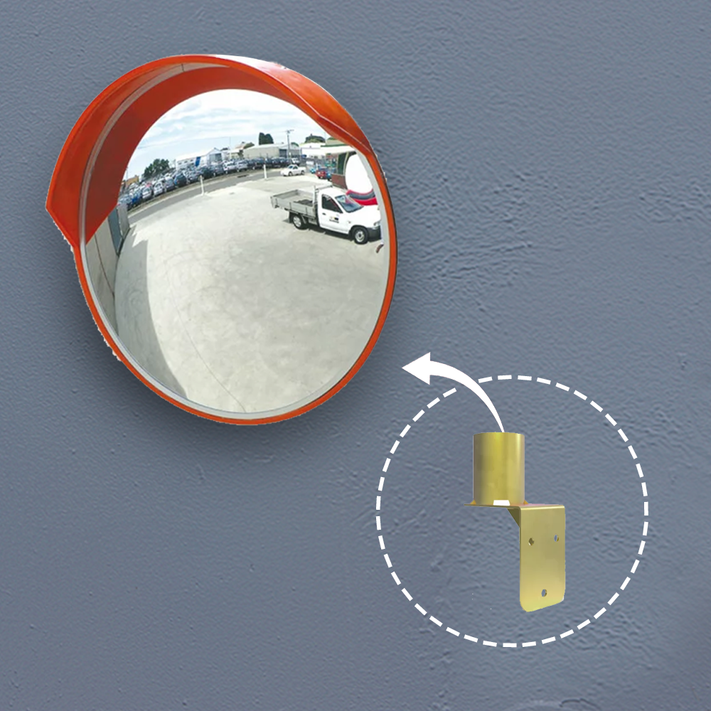 A round convex traffic mirror mounted on a grey wall, reflecting an outdoor industrial setting with parked vehicles. An inset image points to the gold-coloured wall mount bracket, showing its function as a mounting accessory.