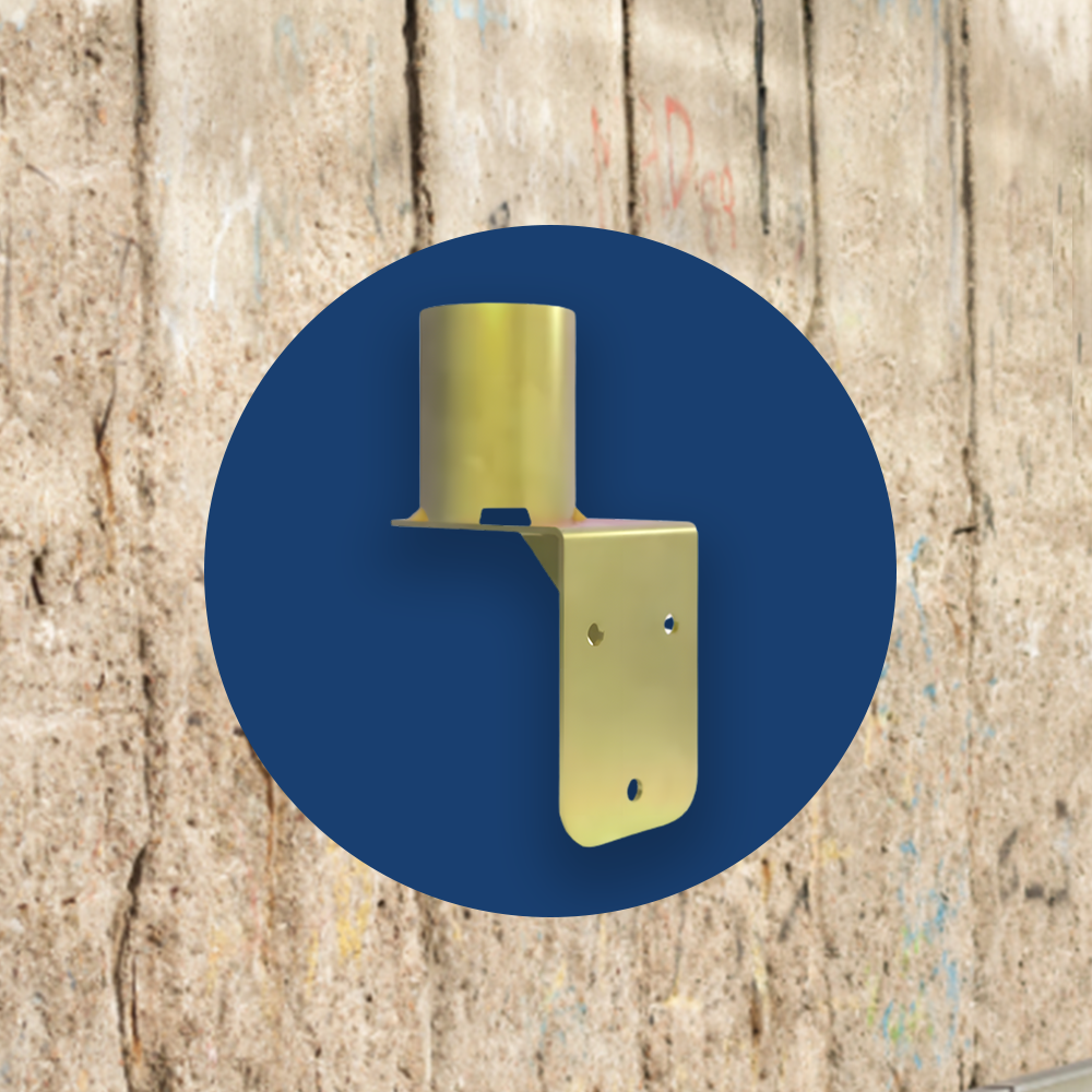 A gold-coloured wall mount bracket displayed against a dark blue circular background with a rough concrete wall behind it. The bracket has a cylindrical top section and a flat, angled base with pre-drilled holes for secure installation.