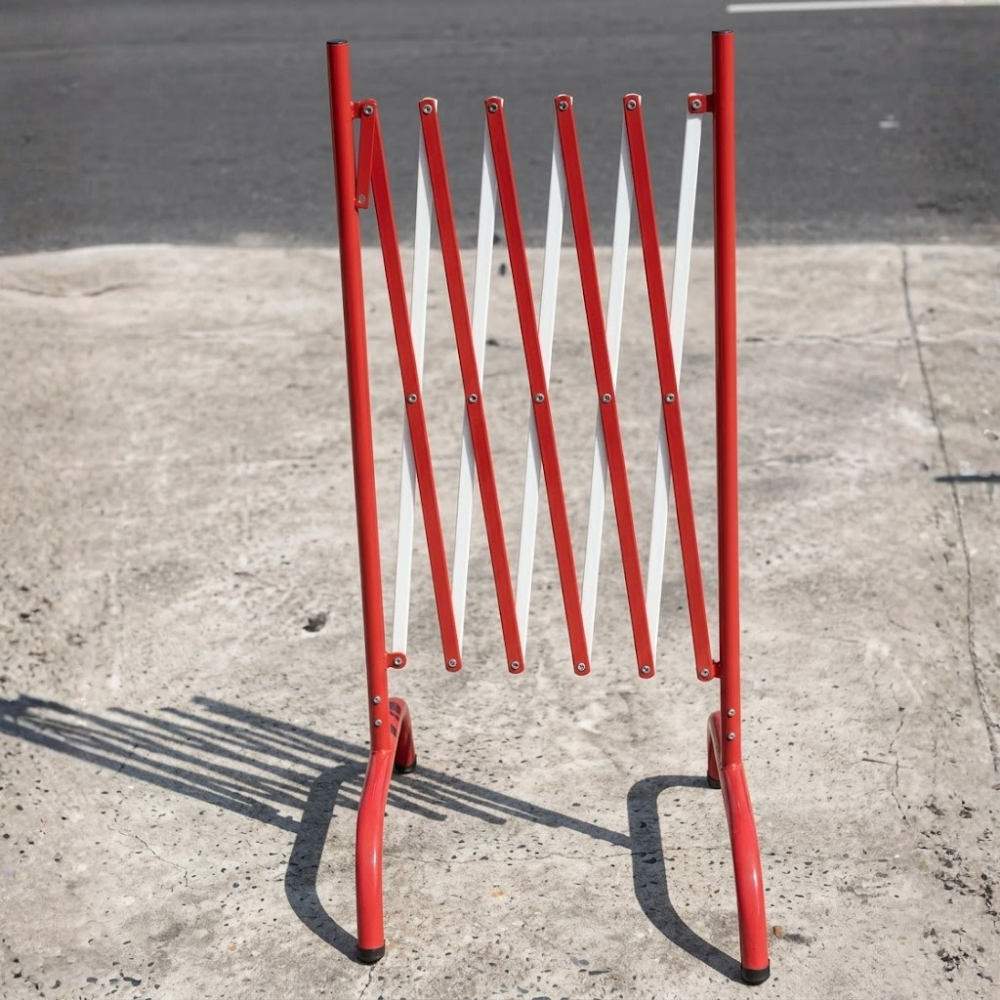 Red metal barrier on a concrete surface with a blurred street background