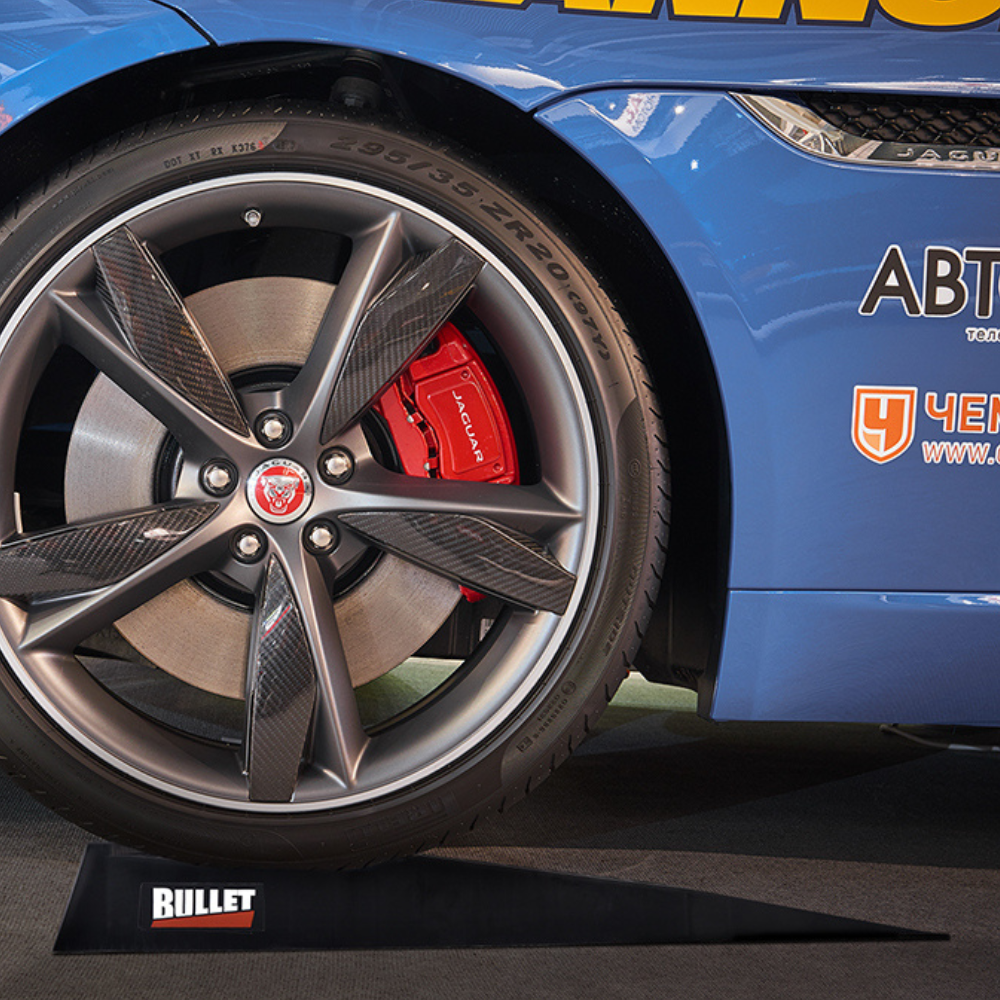 Close-up of a blue car wheel with red brake calipers on a Bullet stand.