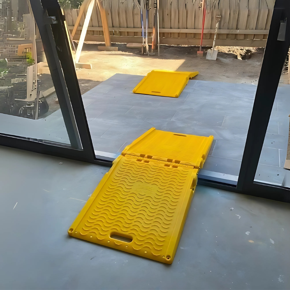 Close-up of yellow ramp in use on a concrete floor at a construction entryway.