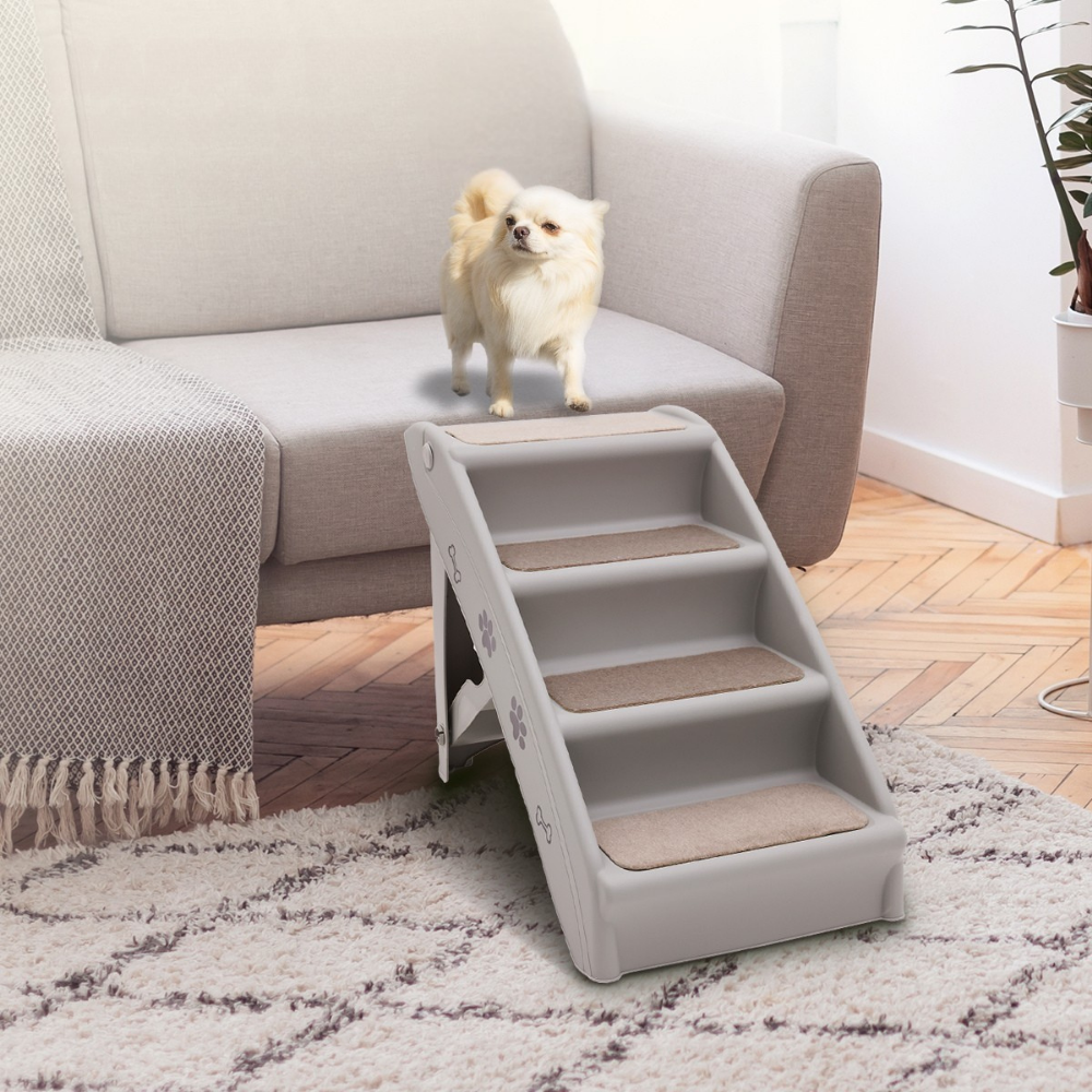 Dog using a set of pet stairs to climb onto a couch in a living room.