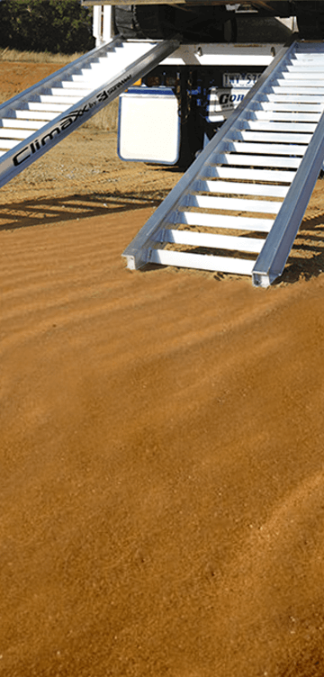 Sureweld loading ramps in dirt against a tip truck