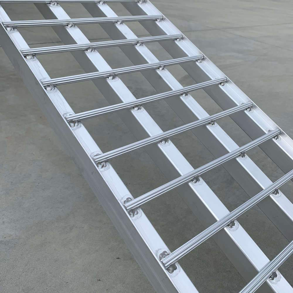 Side view of the reinforced aluminium loading ramp showcasing the evenly spaced, sturdy bars and solid construction on a concrete