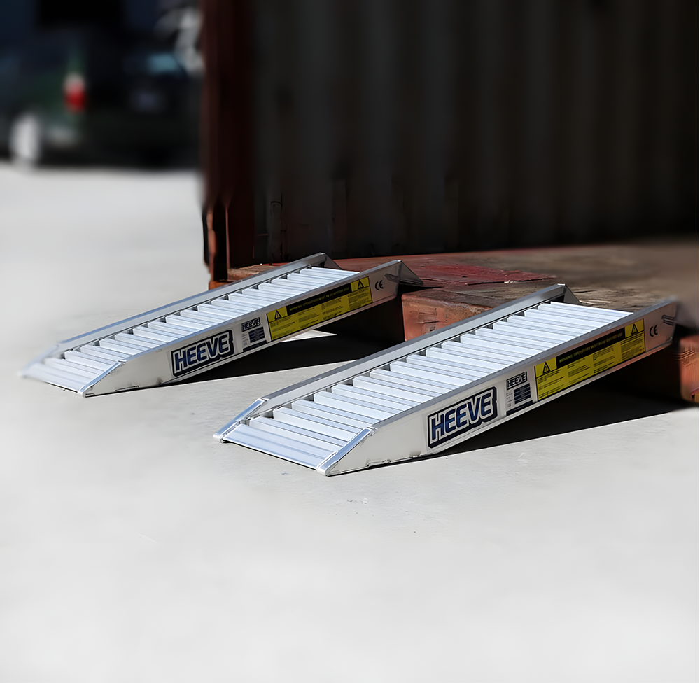 Two Heeve aluminium loading ramps placed at the edge of a platform, designed for easy loading and unloading with raised sides for safety.