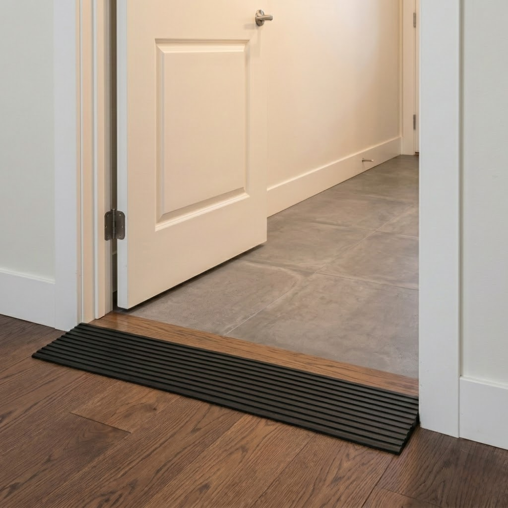Door threshold ramp on a wooden floor with a closed door in the background