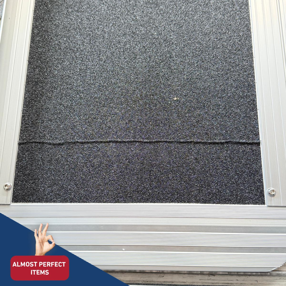 A close-up of a dark gray surface of aluminium ramp, with a small hand gesture and a red badge reading 'ALMOST PERFECT ITEMS' in the lower left corner.
