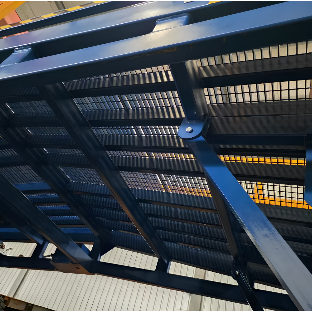 Close-up of a large blue metal industrial structure with slotted grates, beams, and support brackets in a warehouse-like setting.