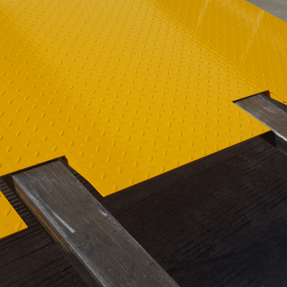 Close up view of Heeve self-supporting forklift container ramp placed in front of an open shipping container, showing the forklift tyne slots and the anti-skid surface.