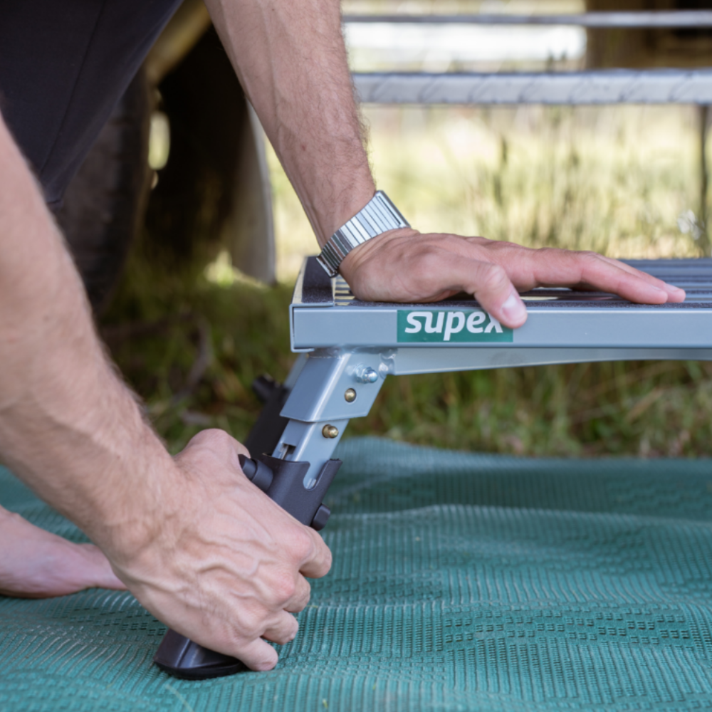 Person using a Super B step stool outdoors on a grassy surface