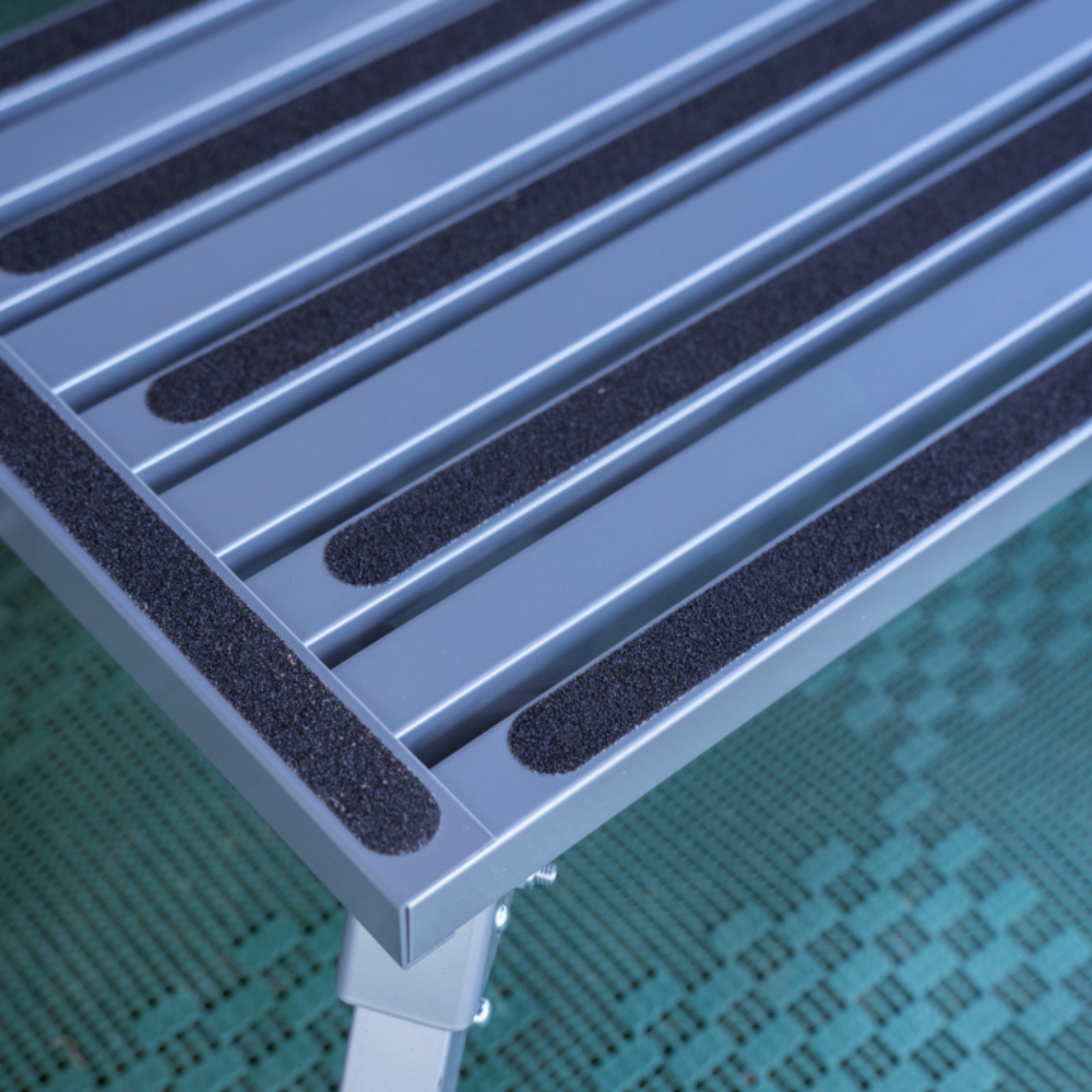 Metallic surface with black rubber strips on a green textured background