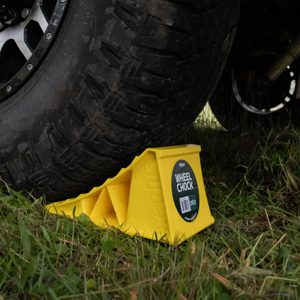 Yellow wheel chock under a tire on grass