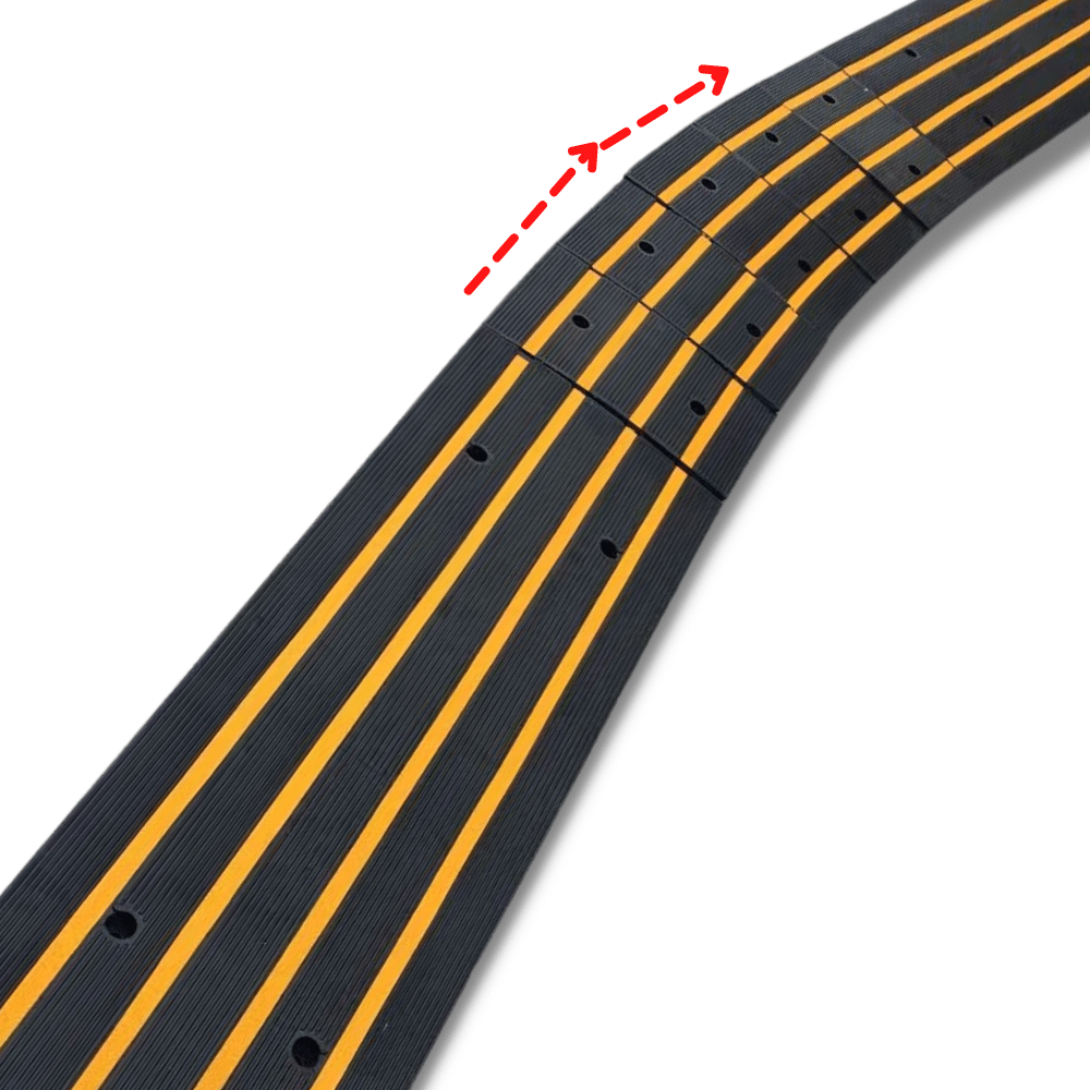 Close-up of a modular black ramp with yellow stripes; red arrows indicate the curved flexibility of the segments.