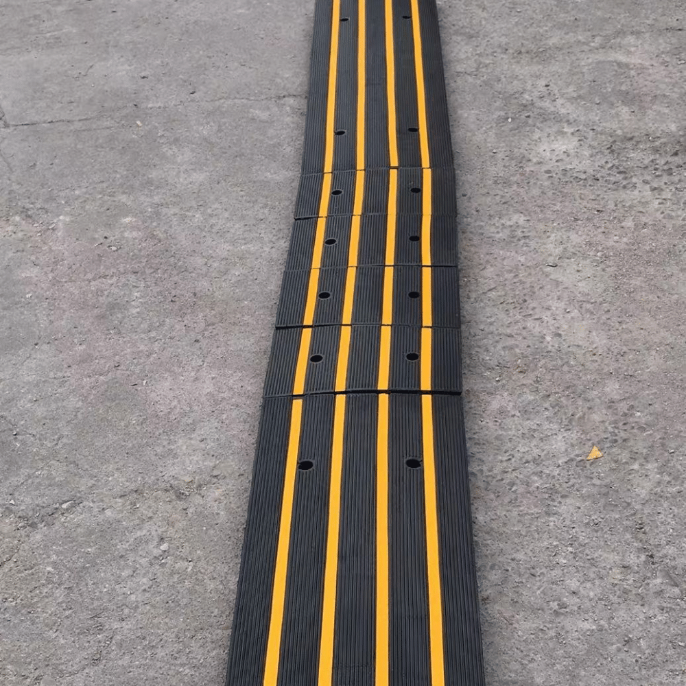 Close-up of a modular black ramp with yellow stripes on concrete floor