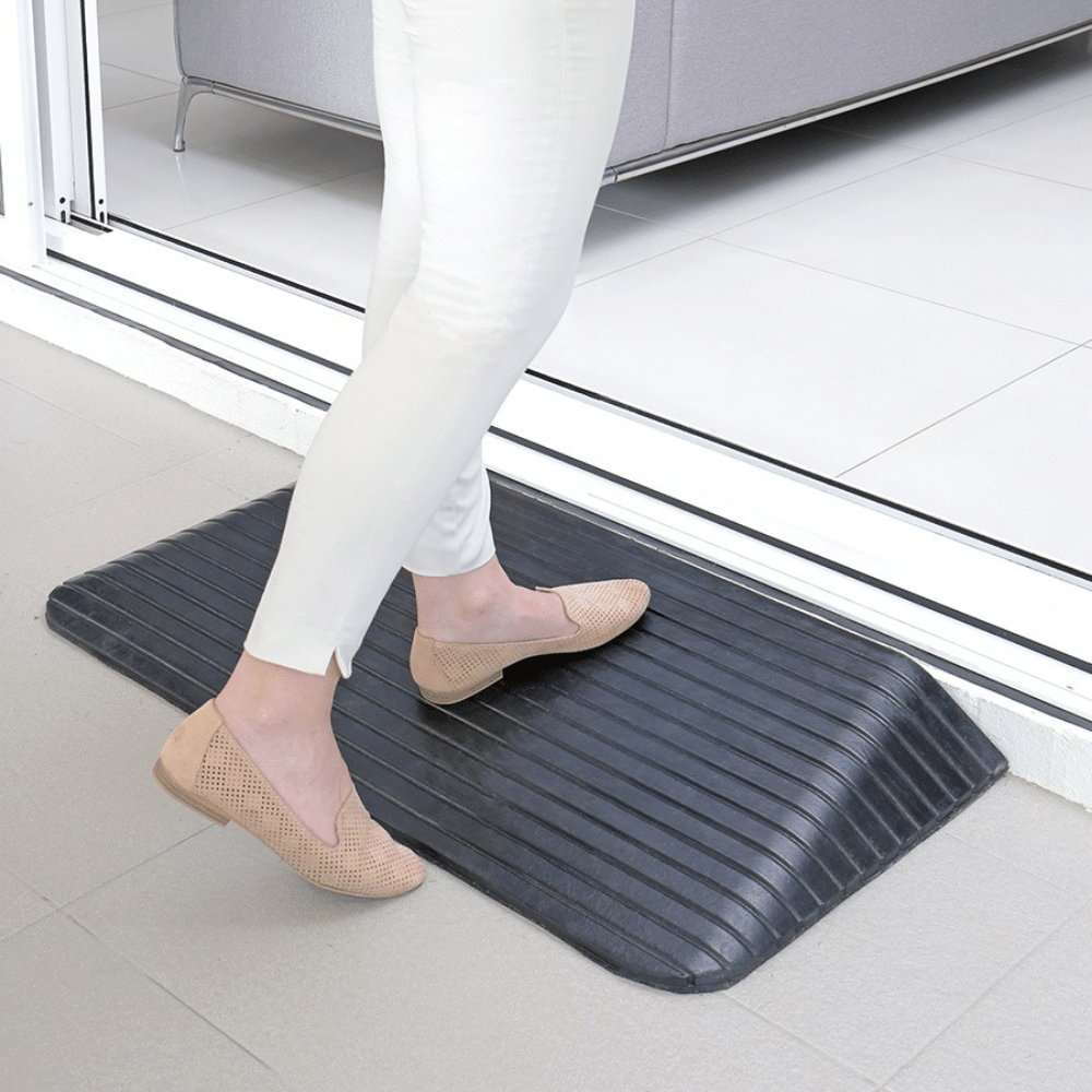 a woman stepping on a black rubber ramp installed on the doorway