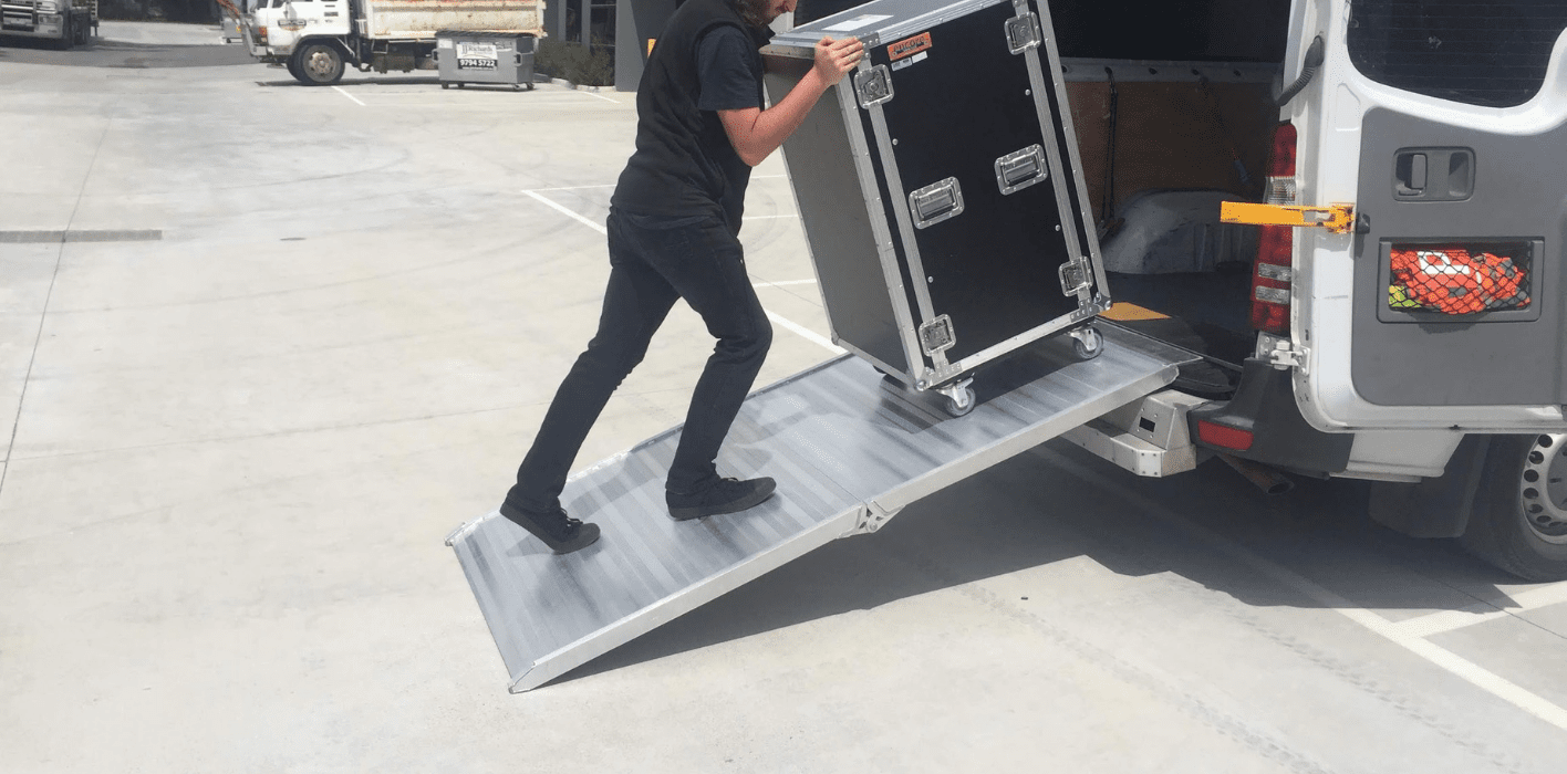 Person walking up a aluminium van ramp with large sound equipment box