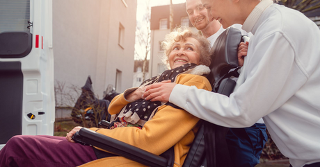 senior on wheelchair assited by nurses and moving towards the vehicle