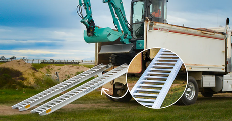 Large Climaxx brand aluminum ramps supporting a teal mini excavator being loaded into the back of a white tipper truck.