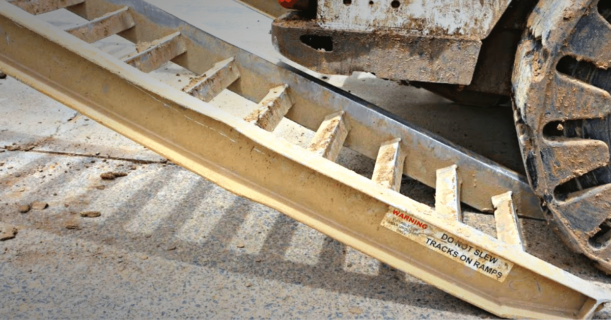 A large-wheeled machine loading a pair of aluminium ramps showing bend beams