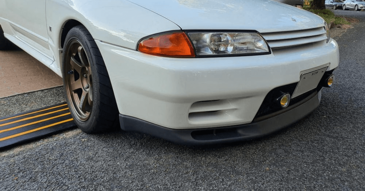 Photo of a lowered white car going downs a rolled edge driveway with a rubber kerb ramp