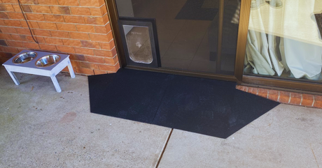 Black rubber threshold ramp at sliding door for smooth entry; pet bowls on left and a pet door fitted in the glass panel. A photo supplied by a long-time customer. 