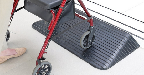 a person with a wheeled walker using a rubber threshold door ramp