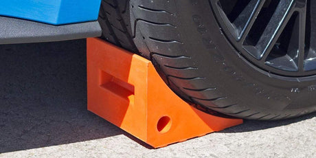a vehicle's wheel resting on orange wheel chock