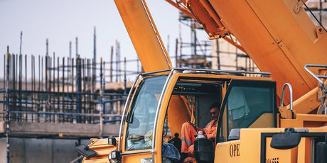 man riding orange heavy equipment in a construction site