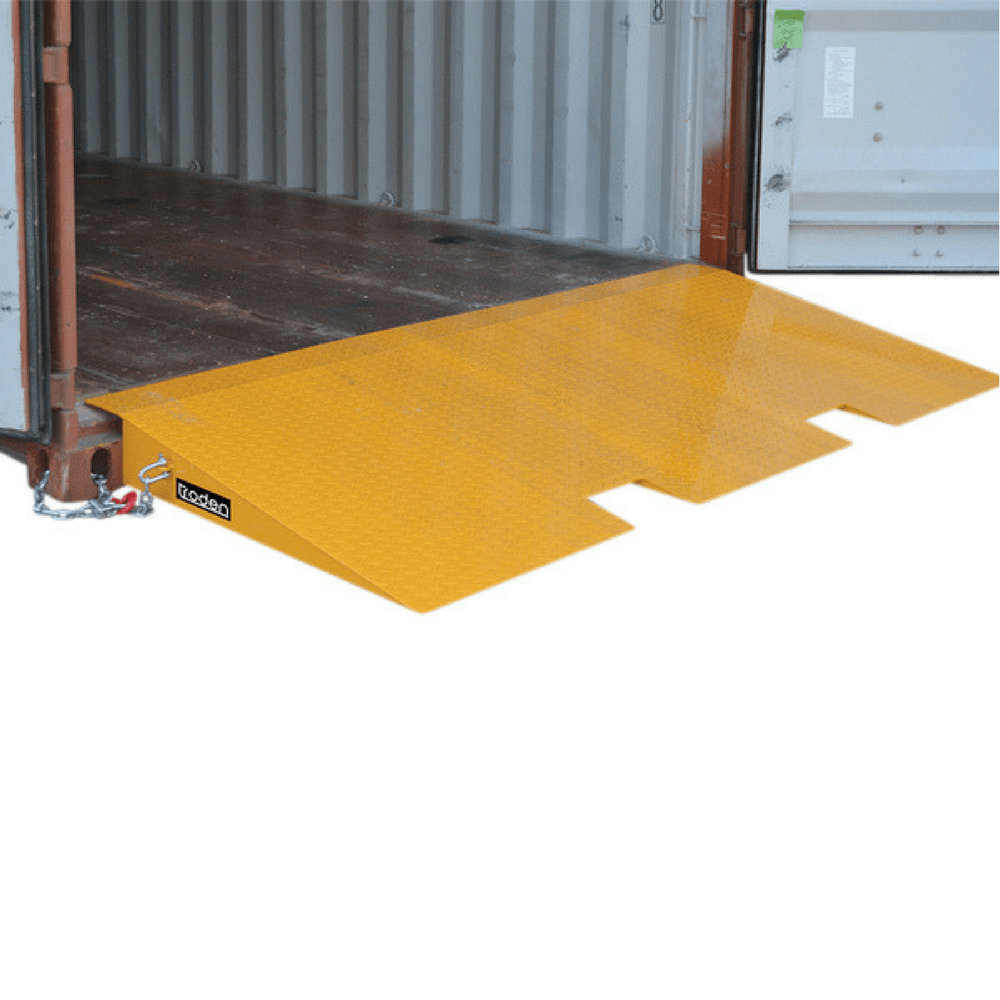 A yellow metal loading ramp with fork pockets sits at the entrance of an open shipping container for easy forklift access.
