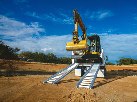 Excavator driven up a pair of Sureweld Track Series aluminium loading ramps onto a tipper truck
