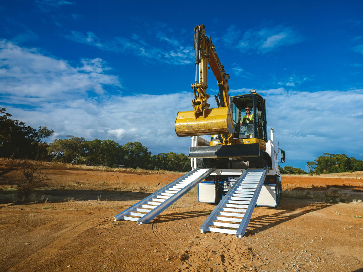 Excavator driven up a pair of Sureweld Track Series aluminium loading ramps onto a tipper truck