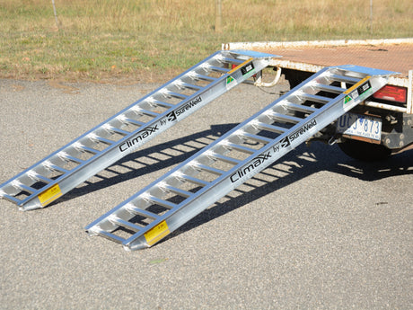 Pair of Sureweld Rubber Series aluminium loading ramps hooked onto the back of a ute tray
