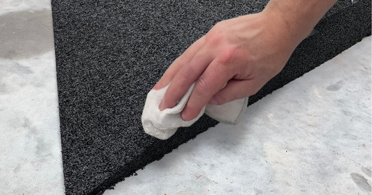 Person cleaning a enviro rubber ramp with a white cloth on a floor.