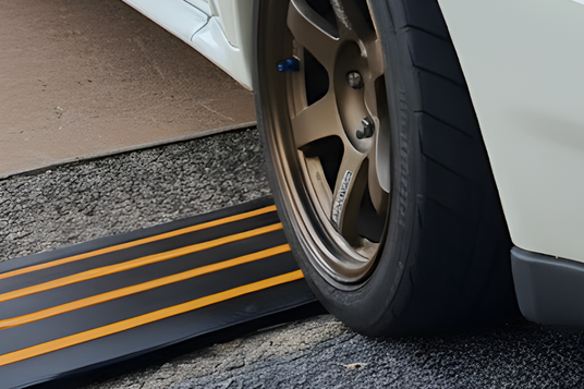 Car wheel on a black and yellow striped rubber kerb ramp