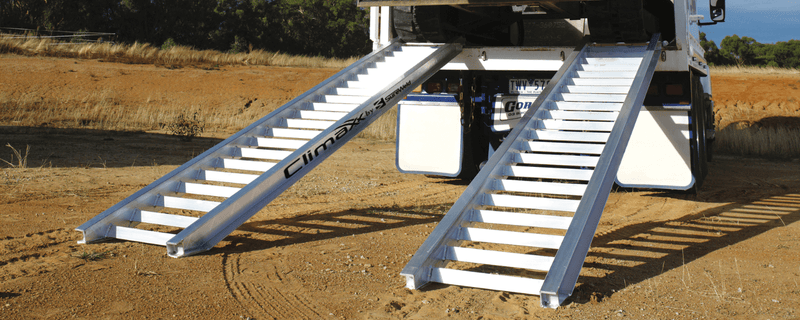 Sureweld construction machinery loading ramps against a truck in the dirt